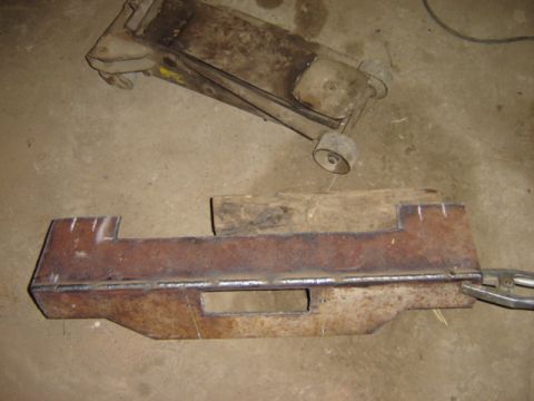 1992 Ford Bronco - A fabricated metal part and a hydraulic jack are shown on a workshop floor.