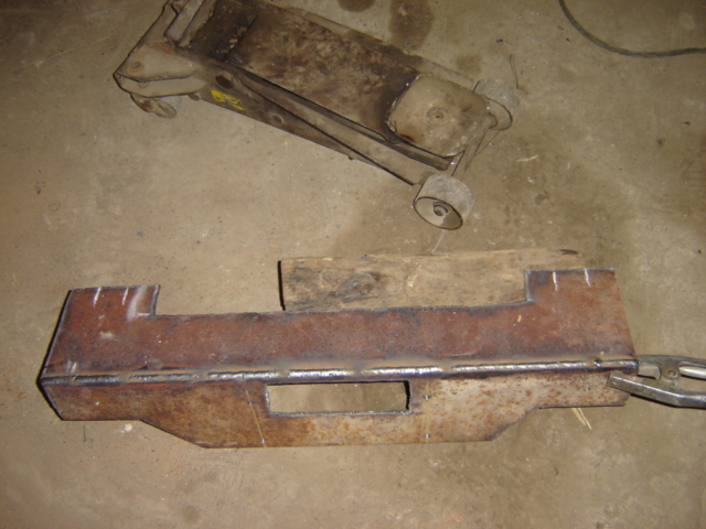 Rusty metal fabrication part and a hydraulic car jack on a concrete floor
