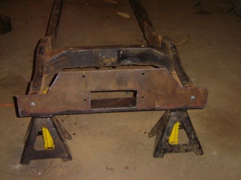 1992 Ford Bronco - A vehicle frame rests on jack stands, with the front crossmember prominently displayed. The frame appears to be a part rather than a comple…