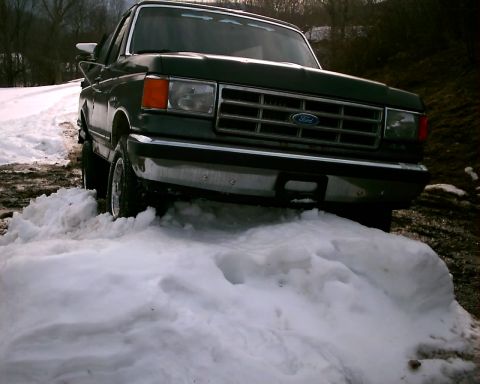 1988 Ford Bronco - Ford truck stuck in snow. Grille suggests a 1987-1991 model year.