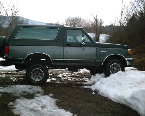 1988 Ford Bronco - This 1988 Ford Bronco is shown in profile, navigating a snowy and muddy terrain.