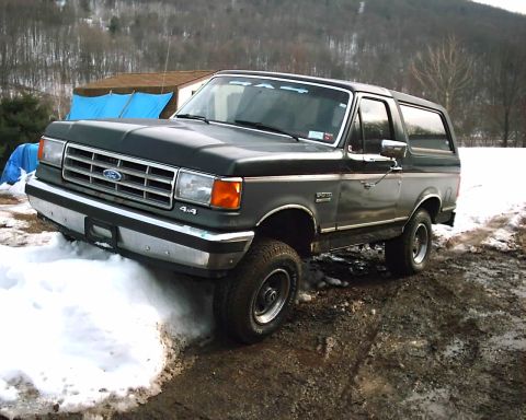 1988 Ford Bronco - Ford Bronco from the late 1980s sits on a dirt and snow-covered path.