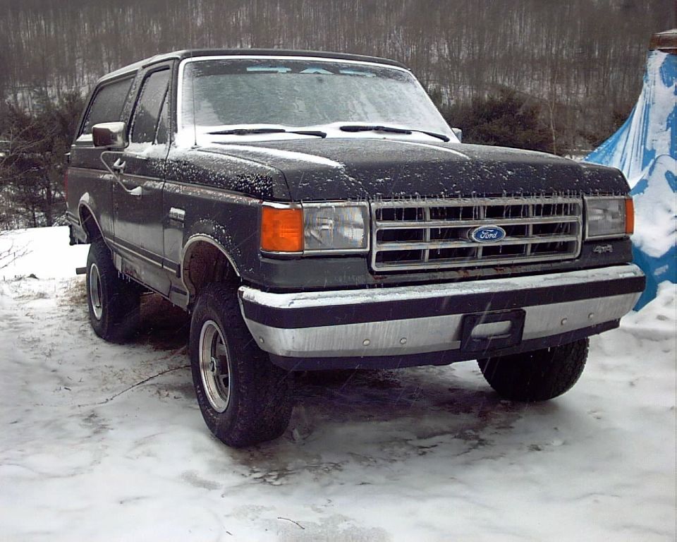 Dark Ford Bronco with snow on it, front 3/4 view, parked in a snowy area