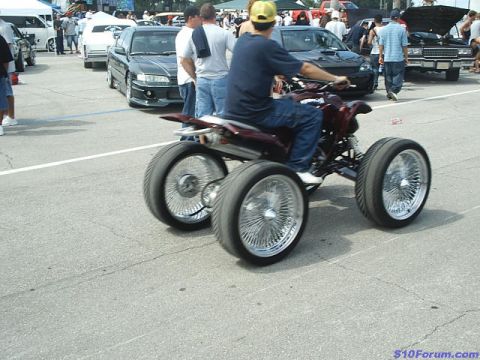 1968 Ford Mustang - Custom ATV with large wire-spoke wheels is shown with other vehicles and people in the background.