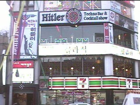 1968 Ford Mustang - Street photo of a multi-story commercial building with illuminated signage for a themed bar, including Korean-language signs and a 7-Eleven…