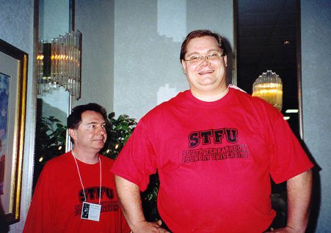 1968 Ford Mustang - Two men pose for a photo indoors, both wearing matching red t-shirts with university text. The man in front is smiling broadly.