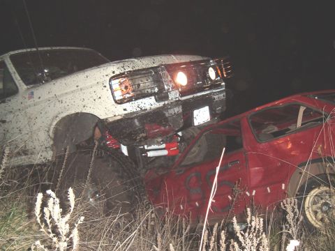 1989 Ford Bronco - Mud-covered 1989 Ford Bronco and a red car are stuck in a field at night.