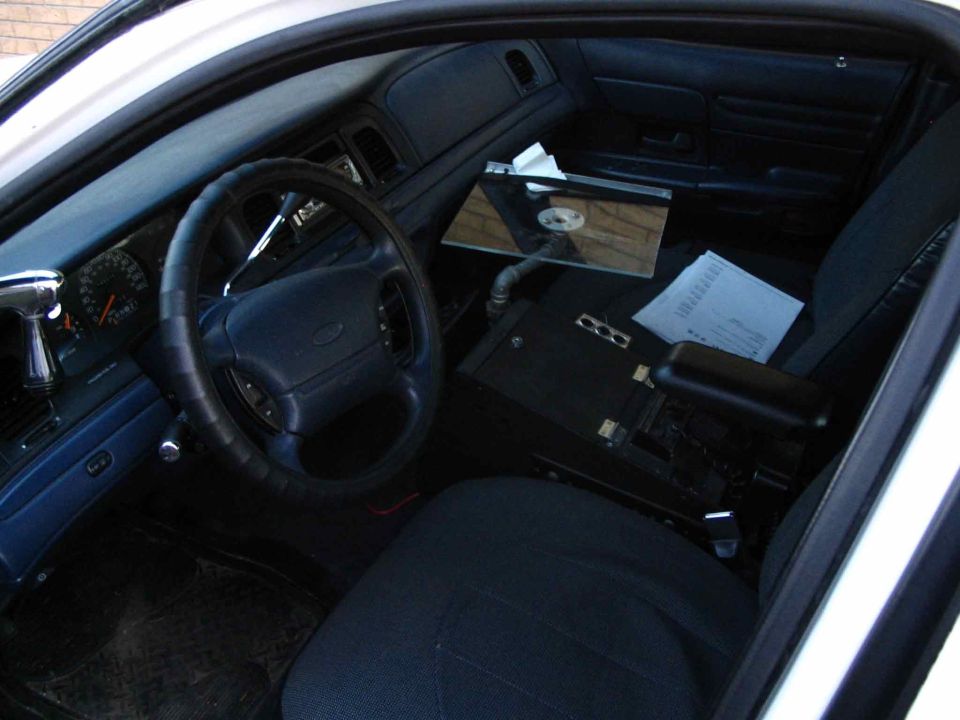 Driver-side interior of Crown Victoria with blue dash, wrapped steering wheel, police-style center console and laptop mount