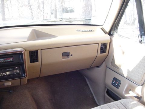 1989 Ford Bronco - The interior of a vehicle shows the dashboard, radio, and glove compartment.