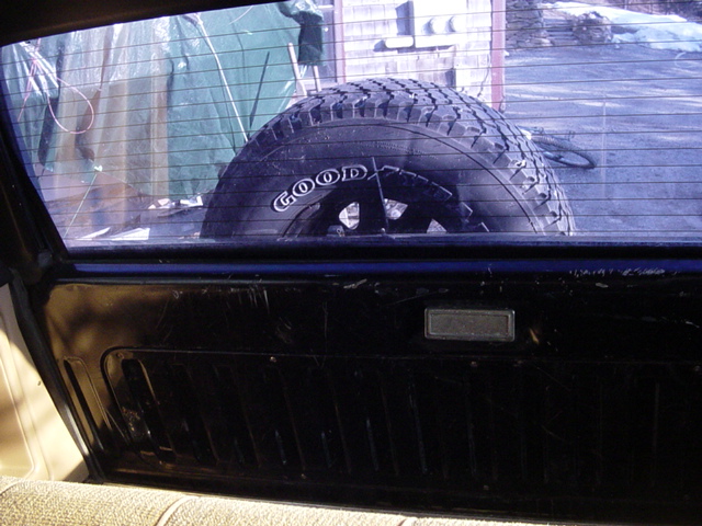 Spare tire mounted inside a 1989 Ford Bronco, seen through the rear window