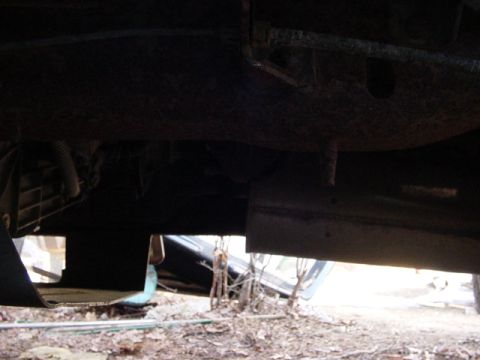 1989 Ford Bronco - A low-angle shot reveals the undercarriage of a vehicle, with a second vehicle partially visible in the distance.