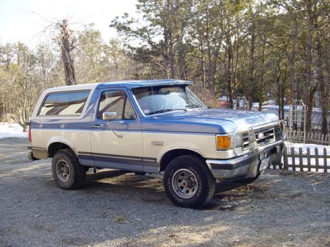 1989 Ford Bronco - This two-tone blue and white Ford Bronco is parked outdoors in a gravel lot.