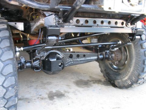 1986 Ford F-150 - Close-up view of the rear axle and suspension system on a heavily modified truck, aftermarket components and large off-road tires.