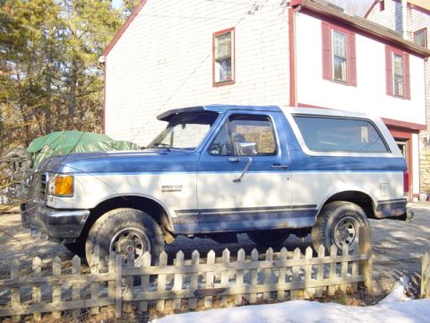 1989 Ford Bronco - This two-tone blue and white Ford Bronco is parked in front of a white house with red trim.
