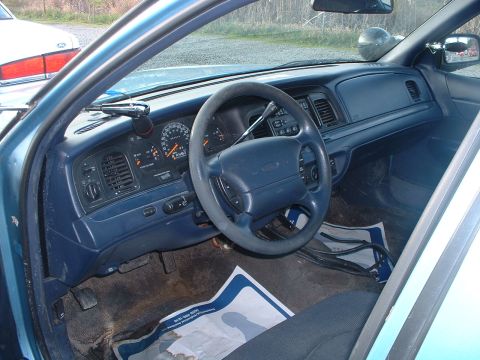 1999 Ford Crown Victoria - Interior view of a 1999 Ford Crown Victoria, showing the dashboard, steering wheel, and police equipment.