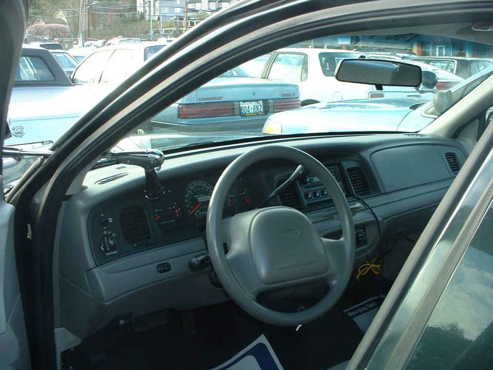Gray dashboard and steering wheel of a 1998 Ford Crown Victoria, seen from passenger side