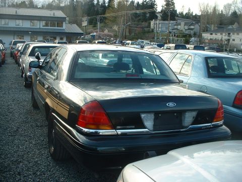 1999 Ford Crown Victoria - Dark Ford Crown Victoria parked in a lot with other vehicles visible.
