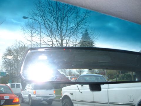 1999 Ford Crown Victoria - View through a vehicle's interior mirror shows traffic including a white SUV and a red car.