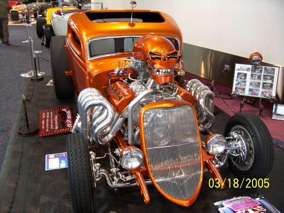 Orange hot rod with a skull for a hood ornament and exposed engine. Date stamp reads 03/18/2005