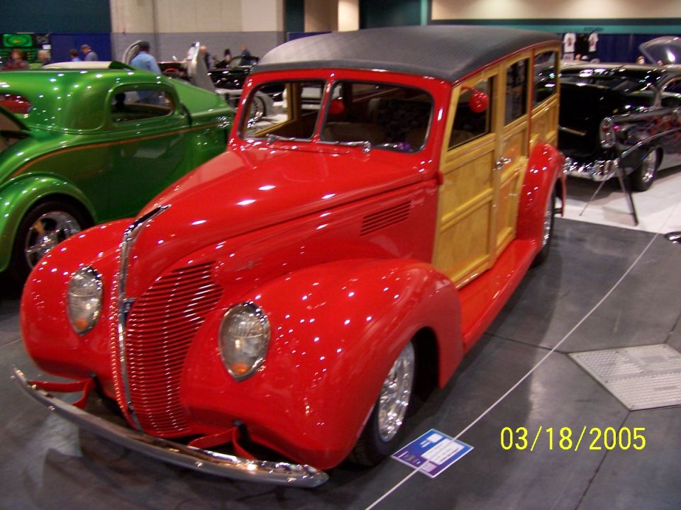 Red and wood-paneled station wagon, front 3/4 view, parked indoors