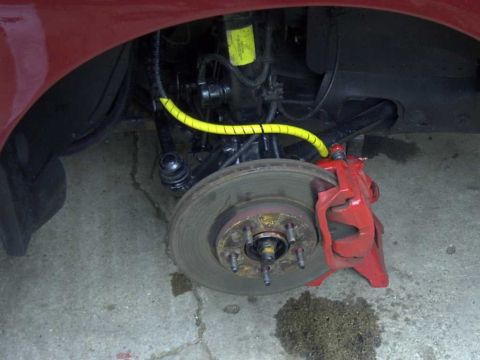 1997 Ford Taurus - Close-up of a vehicle's front brake system, showing the caliper, rotor, and suspension components.