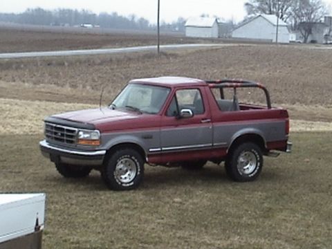 1994 Ford Bronco - This two-tone Ford Bronco is shown from a three-quarter front angle, parked outdoors on a grassy field.