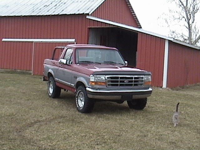 1994 Ford Bronco parked in front of a red barn
