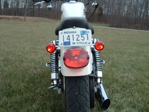 1995 Mercury Grand Marquis - The rear of a white motorcycle is shown with an Indiana license plate and red taillights.