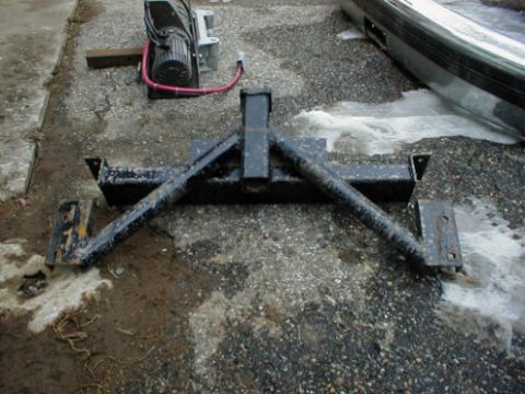 1995 Ford Bronco - A winch and a plow mount assembly are shown on the ground, with a portion of a vehicle bumper visible in the background.