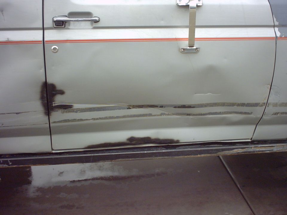 Silver Ford Bronco door with rust damage and a red stripe