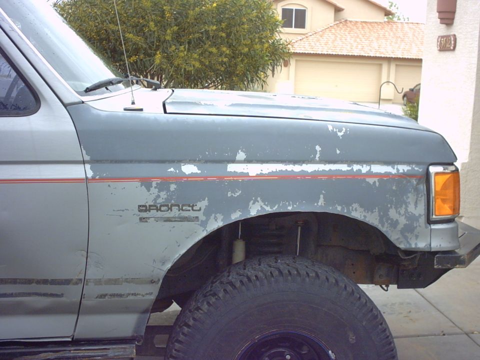 Gray and blue 1990 Ford Bronco fender with peeling paint and red stripe