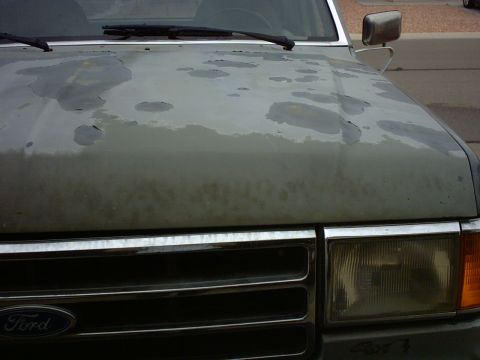 1990 Ford Bronco - The paint on this Ford Bronco's hood is severely damaged, showing significant peeling and discoloration.