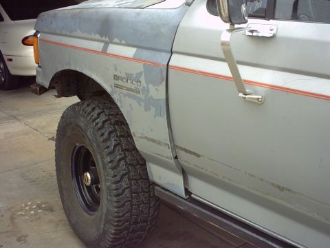 1990 Ford Bronco - Side view of a 1990 Ford Bronco, with another vehicle partially visible in the background.