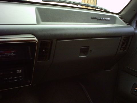 1990 Ford Bronco - Interior view of a 1990 Ford Bronco dashboard, showing the passenger side with a glove box and air vents.