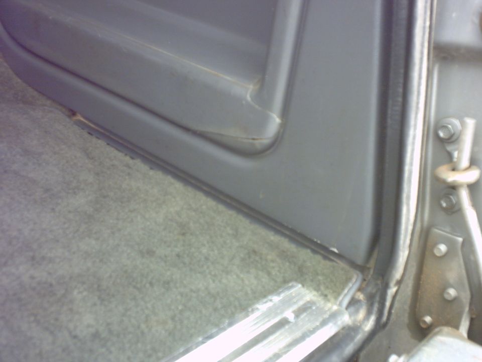 close-up of gray interior door panel and carpet, with door latch visible