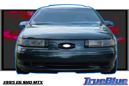 1993 Ford Taurus - Frontal view of a dark sedan with its headlights illuminated against a dark background.