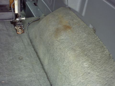 1990 Ford Bronco - The interior carpet of a vehicle shows wear and some stains.
