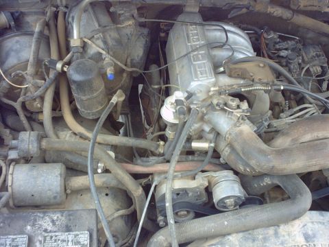 1990 Ford Bronco - Close-up view of a Ford V8 engine bay with visible intake manifold and hoses. Supermotors.net watermark present.