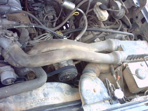 1990 Ford Bronco - Close-up view of a vehicle's engine compartment, showing various mechanical components and hoses.