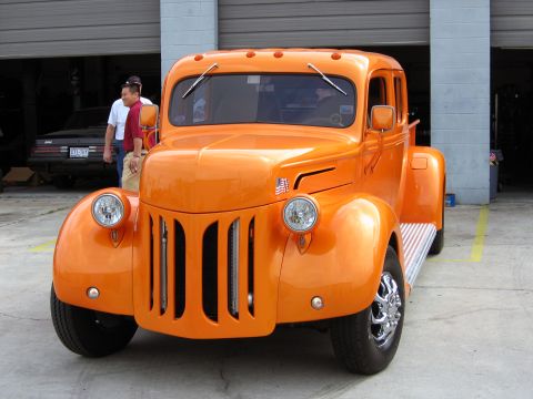 2000 Ford Crown Victoria - Front view of a bright orange custom hot rod truck parked indoors.