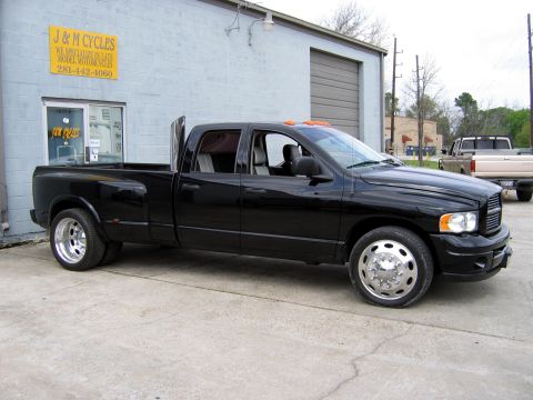 2000 Ford Crown Victoria - A black dually pickup truck is parked in front of a building with a "J & M Cycles" sign.