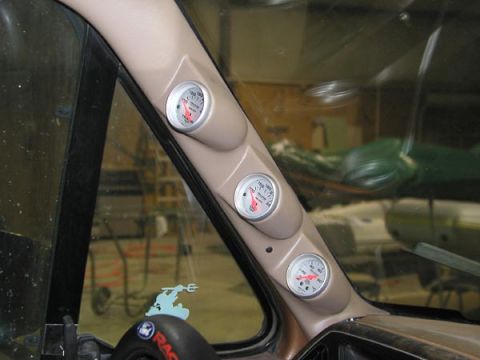 1988 Ford Bronco - Aftermarket gauges are installed on the A-pillar of the vehicle's interior.
