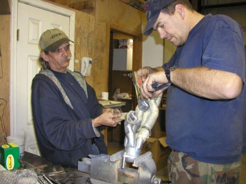 1988 Ford Bronco - Two men work on an exhaust manifold in a garage setting.