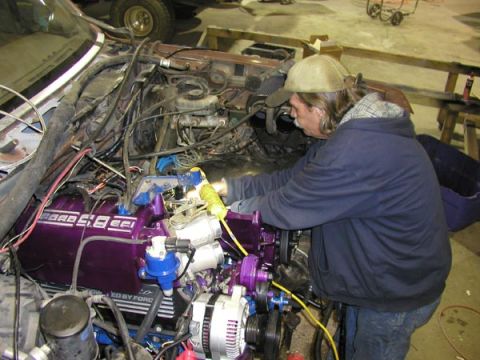1988 Ford Bronco - Man working on the engine of a 1988 Ford Bronco, purple valve covers.