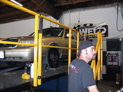 2000 Ford Crown Victoria - A gold 2000 Ford Crown Victoria is positioned on a lift in a garage setting.