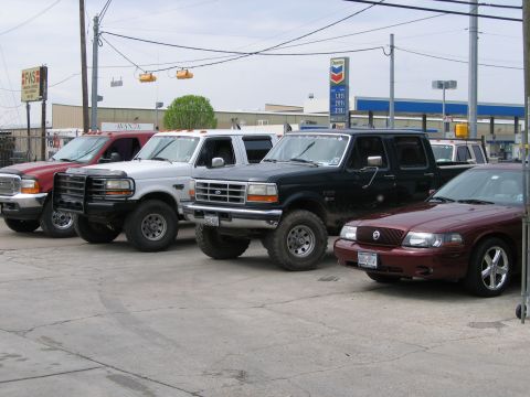 2000 Ford Crown Victoria - A maroon sedan is parked in front of several trucks.