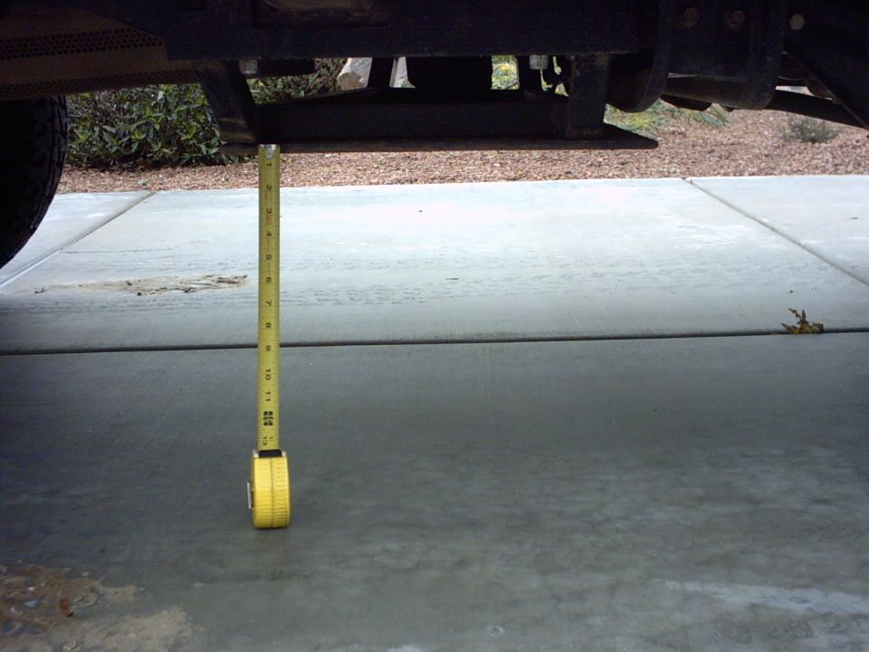 Measuring tape hanging from vehicle frame, showing ground clearance