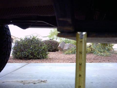 1990 Ford Bronco - Measuring ground clearance of vehicle undercarriage. Tire visible on left.