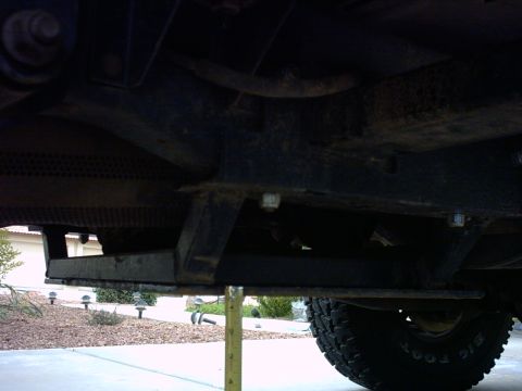 1990 Ford Bronco - The underside of a vehicle is shown, with a tape measure indicating height from the ground.