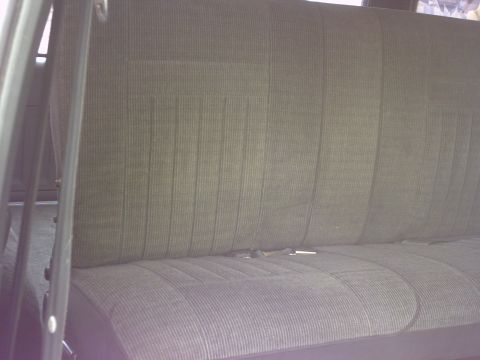 1990 Ford Bronco - Interior view of a car's rear seat, showing the textured fabric and seatbelts.